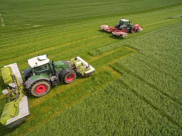 Zwei Traktoren beim Gras mähen Zwei Traktoren beim Gras mähen