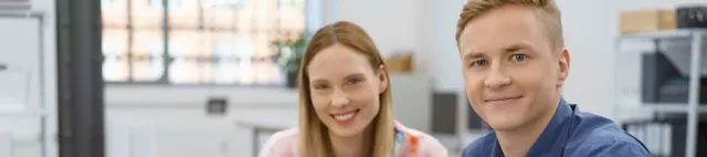 Zwei junge Menschen sitzen an einem Tisch mit Laptop